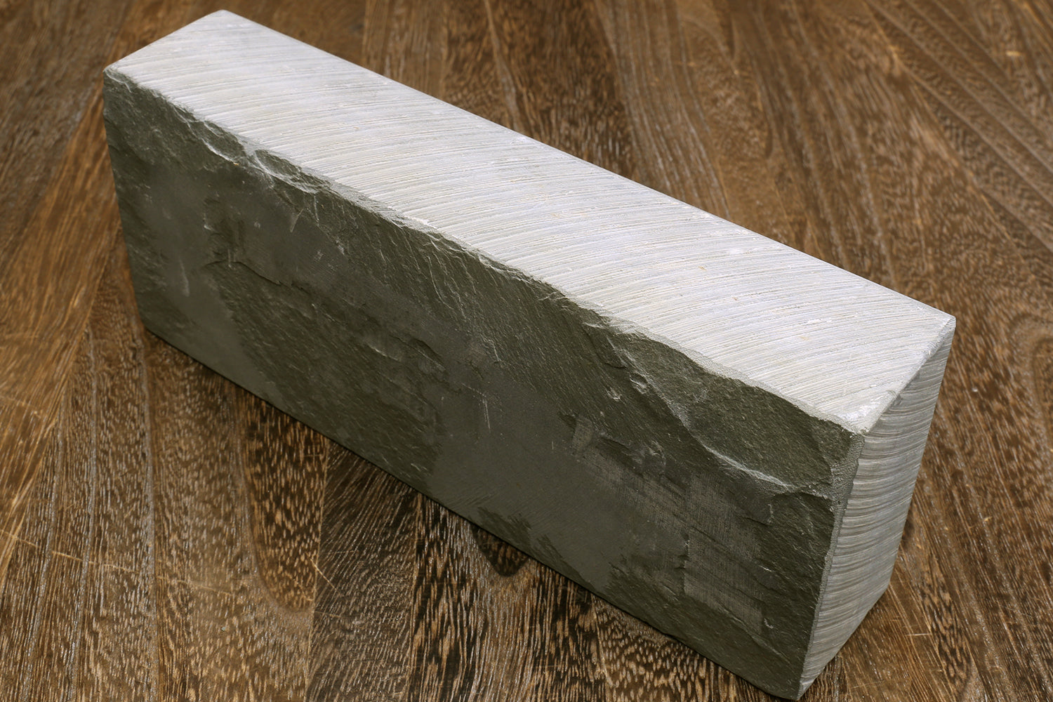 Rectangular dark-grey natural whetstone block, textured sides, no labels visible