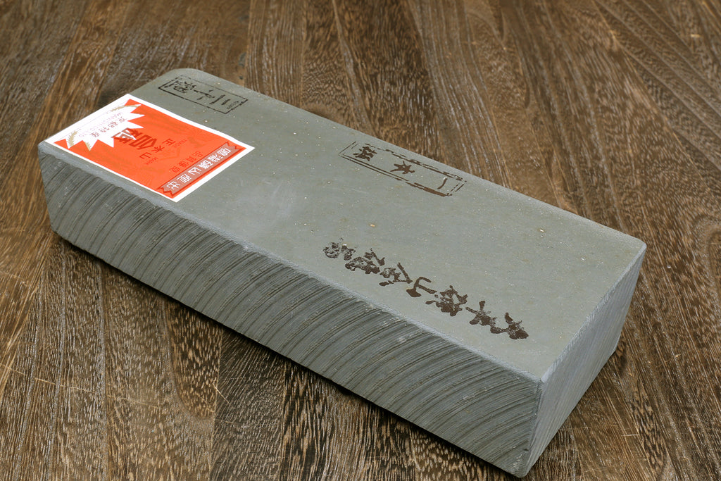 Rectangular grey natural sharpening whetstone with paper label on top