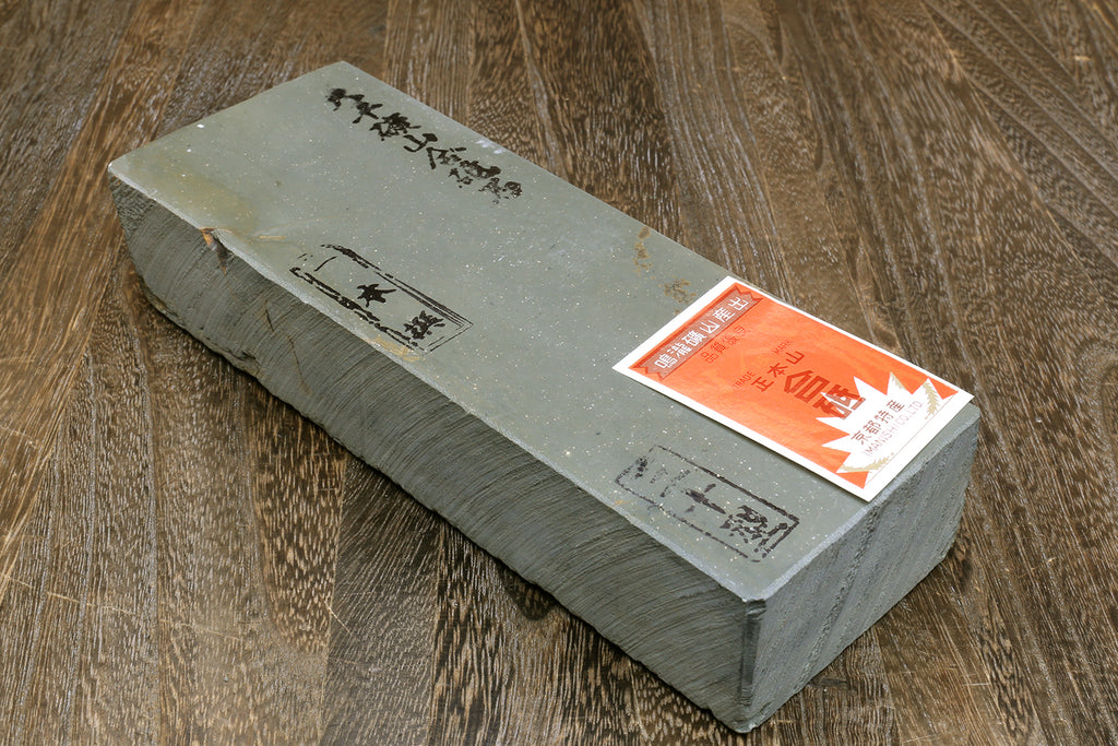 Natural sharpening whetstone with orange label and engraved markings on gray top