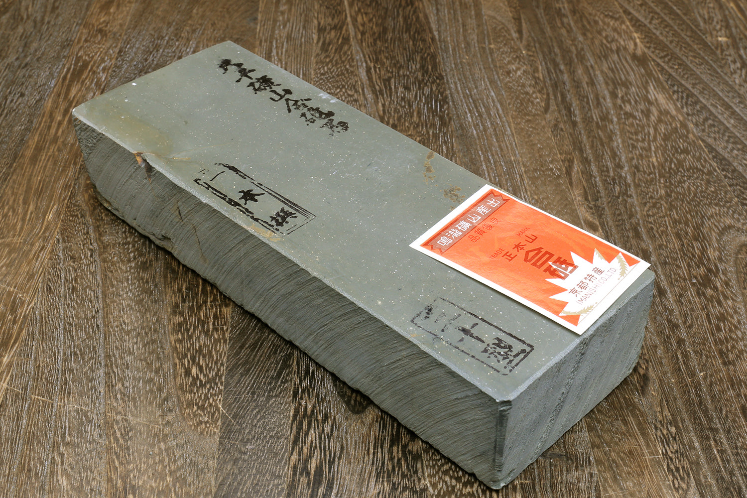Natural sharpening whetstone with orange label and engraved markings on gray top