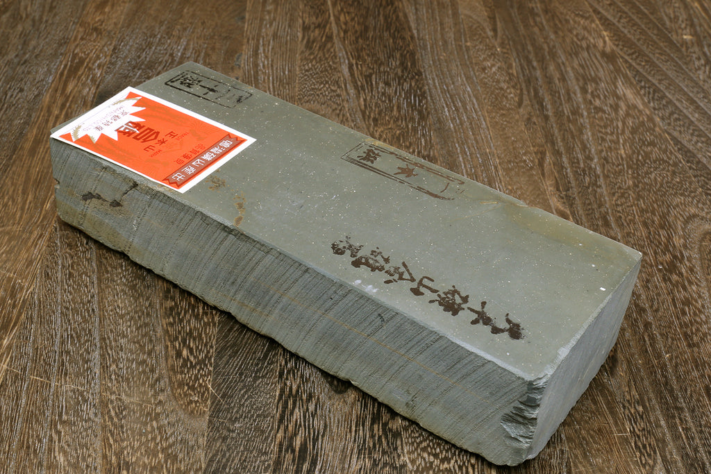 Natural sharpening whetstone block, gray stone with shipping labels on the side
