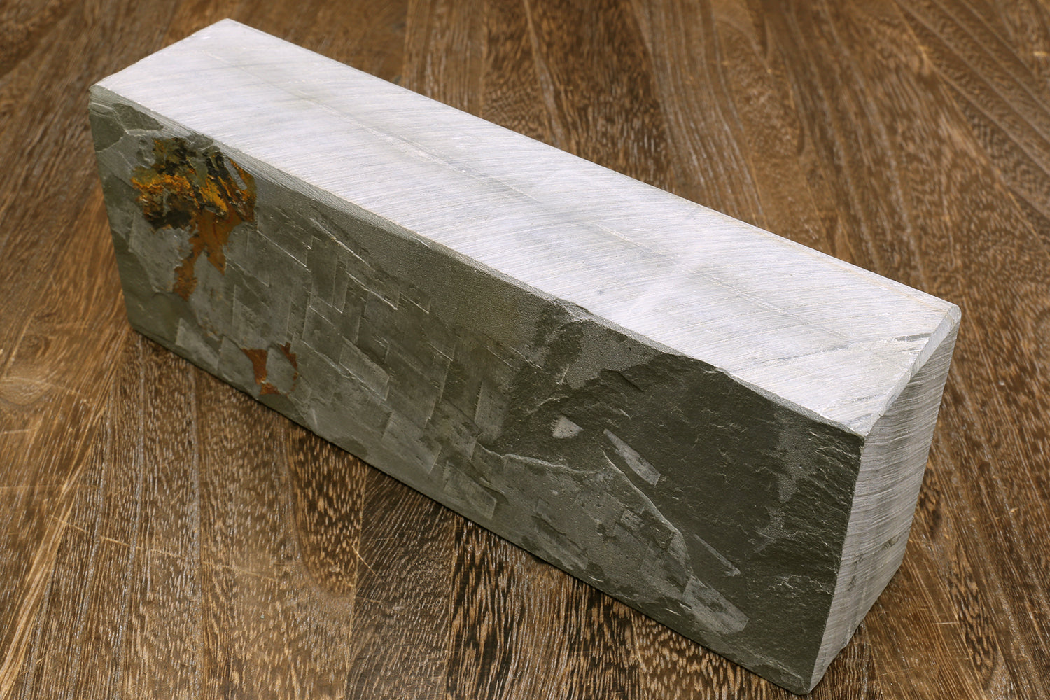 Natural sharpening whetstone, side view of long rectangular gray stone with stamped marks