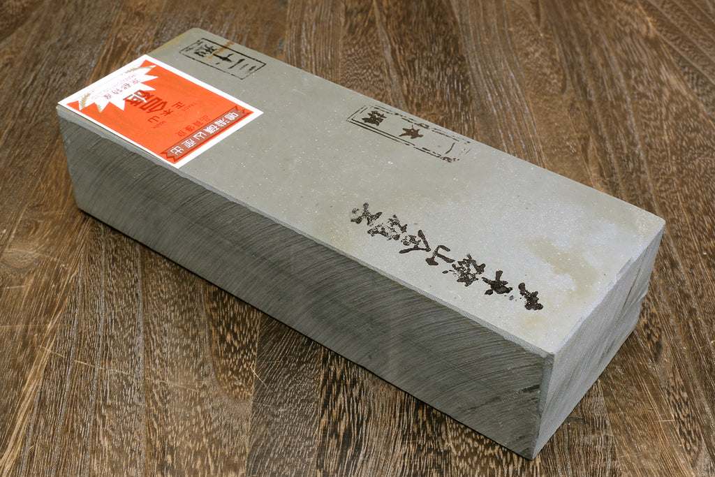 Natural sharpening whetstone, long rectangular gray stone with orange label and markings