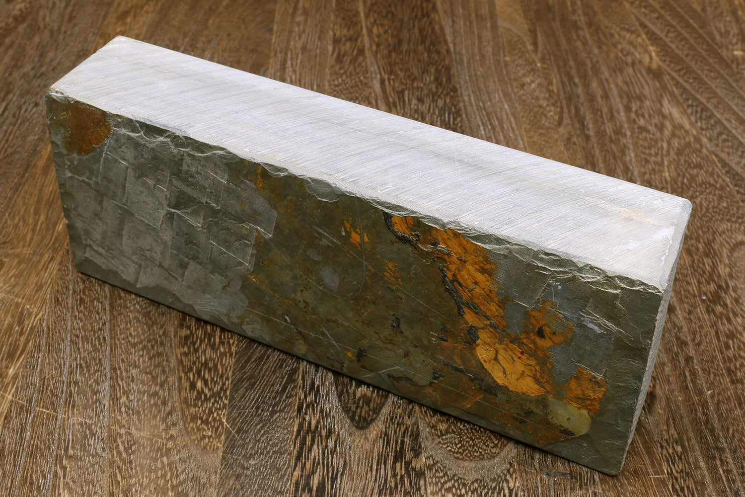 Natural sharpening whetstone, speckled gray block with orange-brown streak