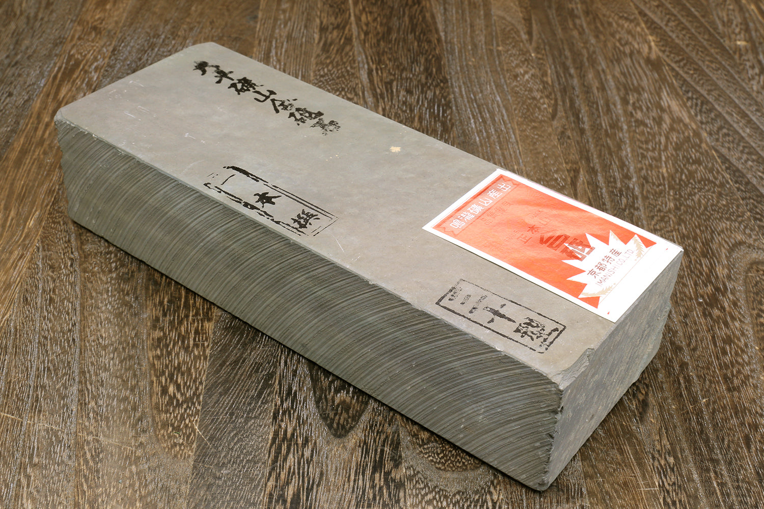 Finishing whetstone with stacked dark gray-green block, paper labels and red sticker on top