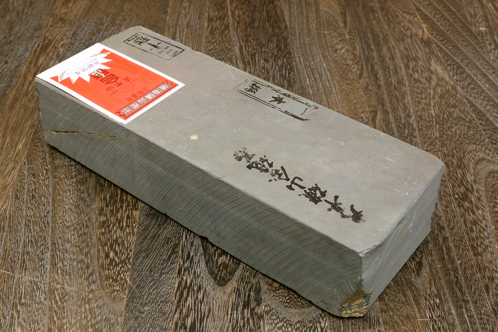 Finishing whetstone block, dark gray-green with printed paper labels and red corner sticker
