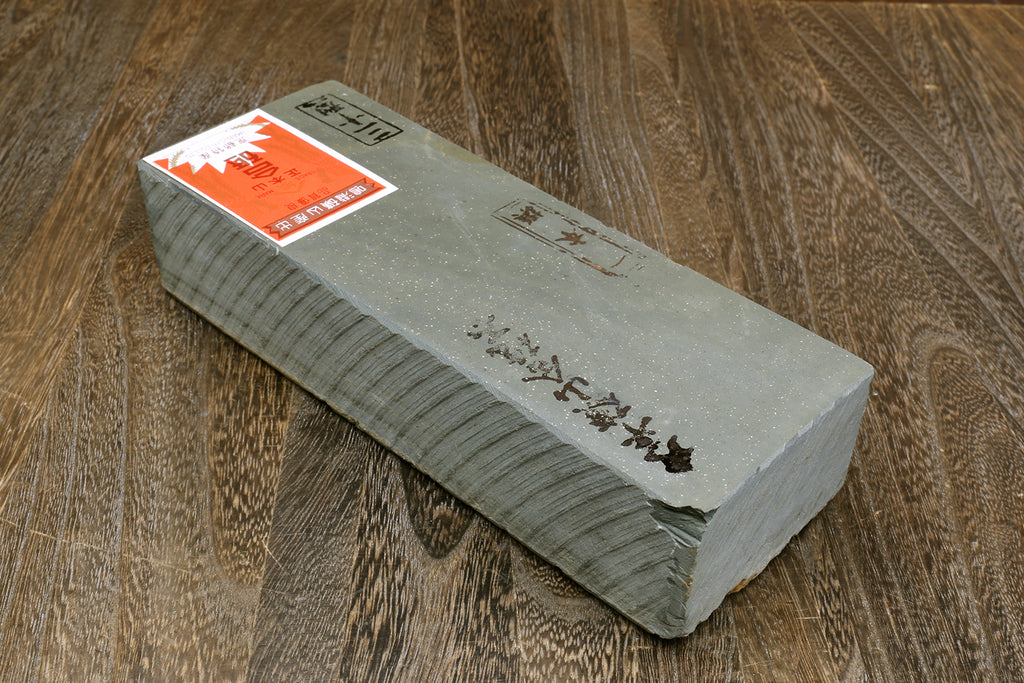 Natural whetstone finishing stone, grey rectangular bar with orange label on top