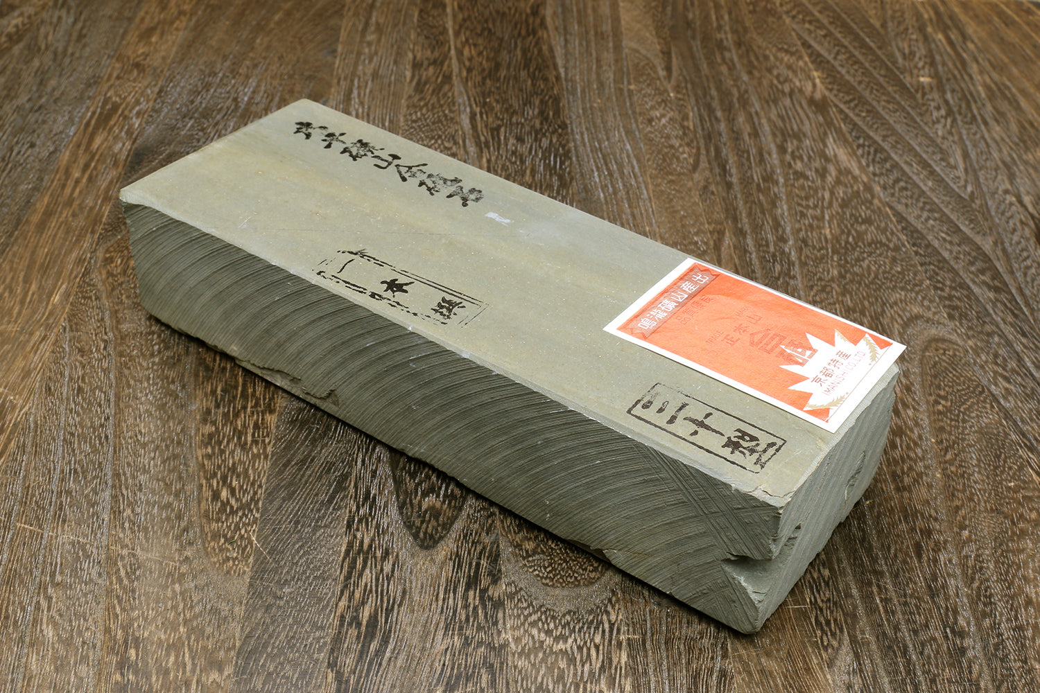 Natural sharpening whetstone in gray wrap with printed label and orange badge