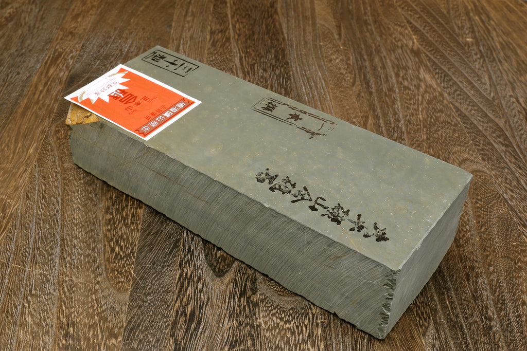 Natural whetstone block, light gray rectangular stone with orange label sticker