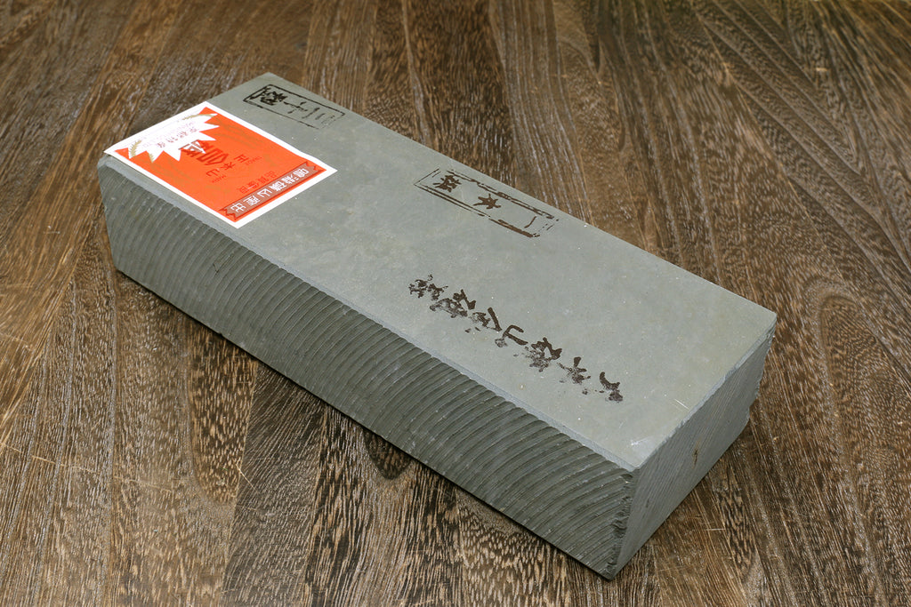 Rectangular gray whetstone with printed label on top and textured sides