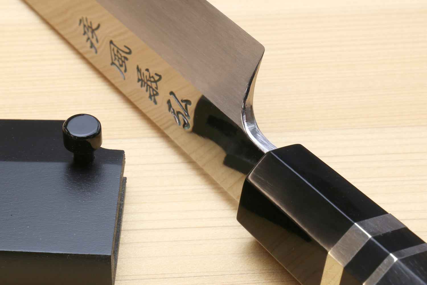 Yoshihiro yanagi sushi knife with mirrored blade markings and ebony handle on black saya