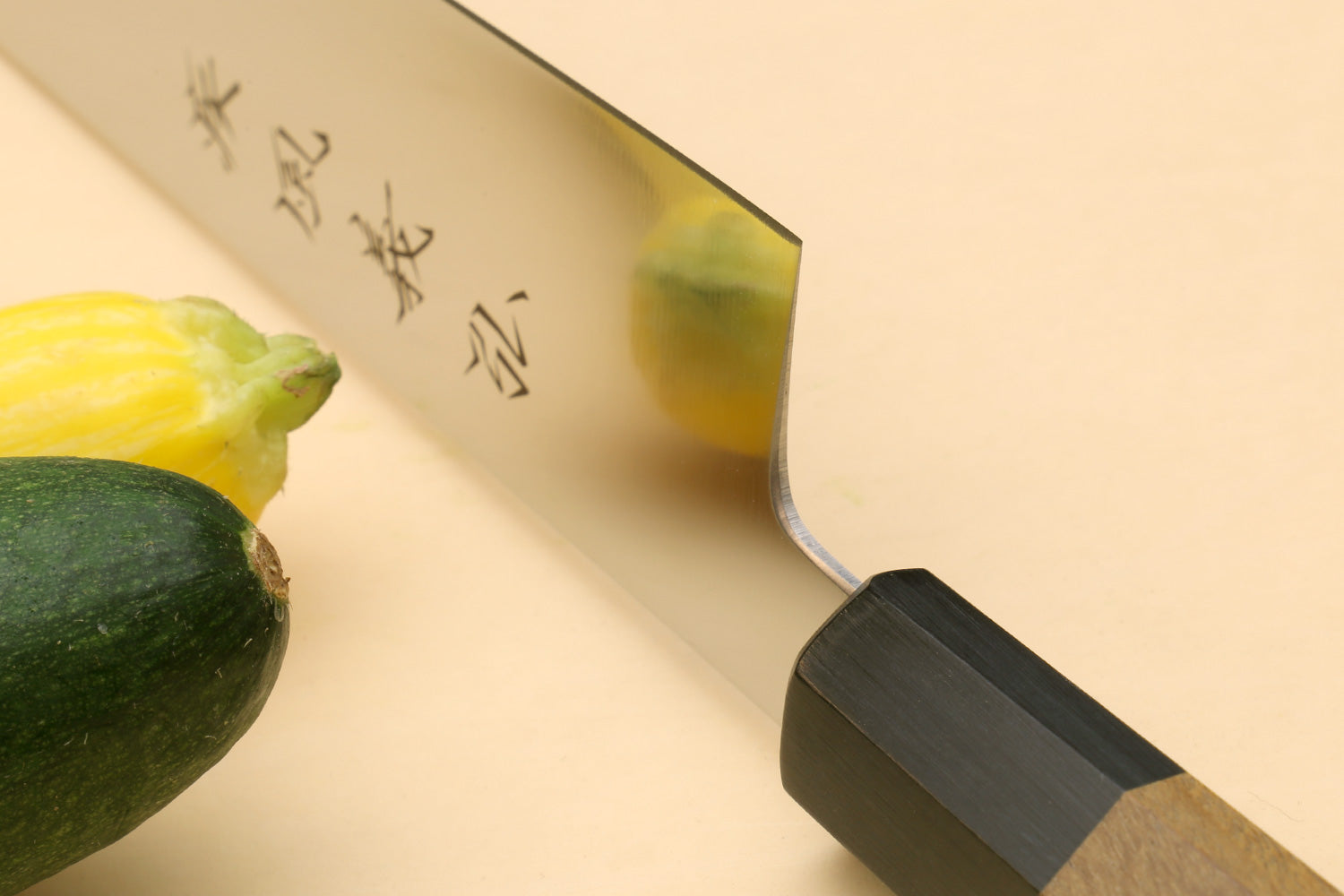 Japanese slicer knife with silver blade edge and dark black bolster on wooden handle