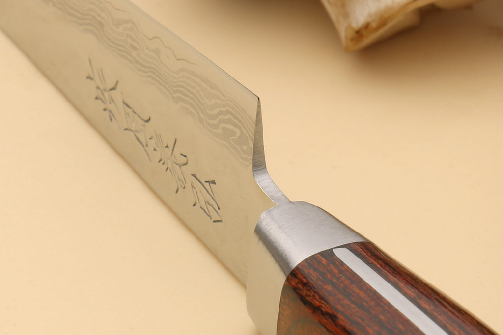 Paring knife close-up of Damascus blade pattern and dark brown wood handle
