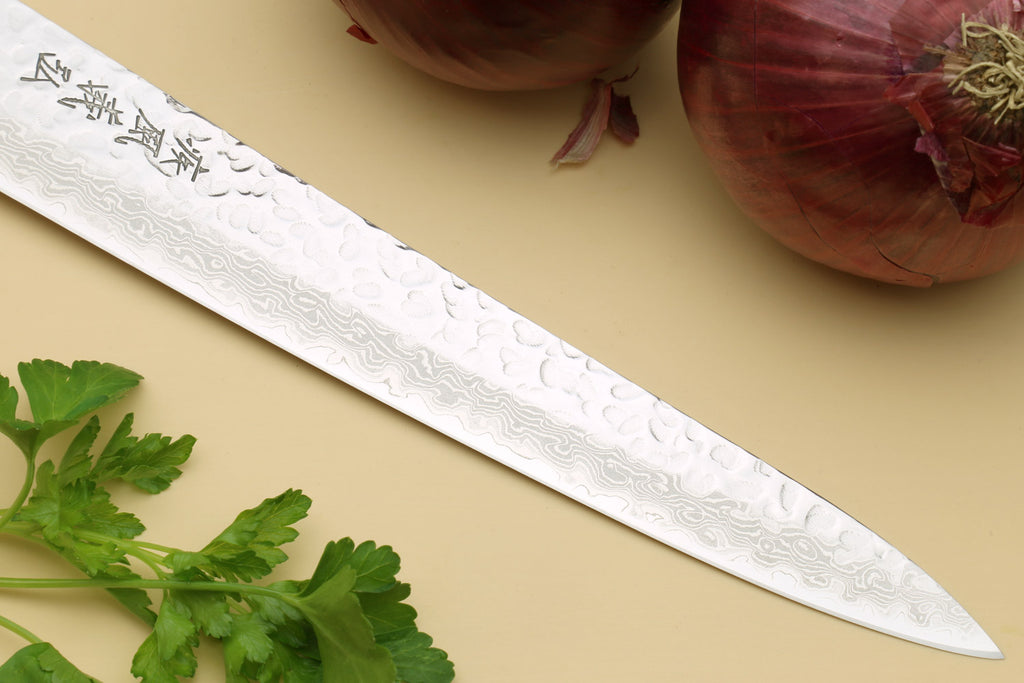 Sujihiki knife close-up of hammered Damascus blade with engraved marks