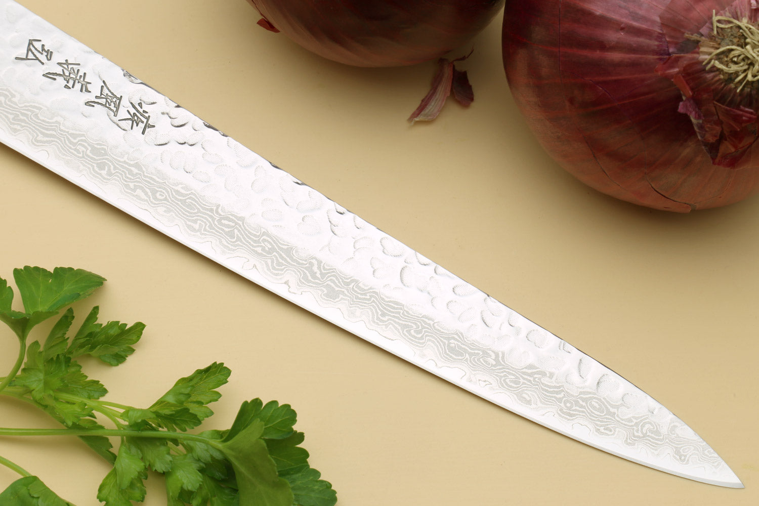 Sujihiki knife close-up of hammered Damascus blade with engraved marks