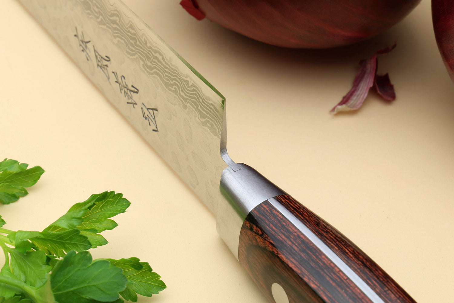 Sujihiki knife side close-up showing hammered Damascus blade and dark wood handle
