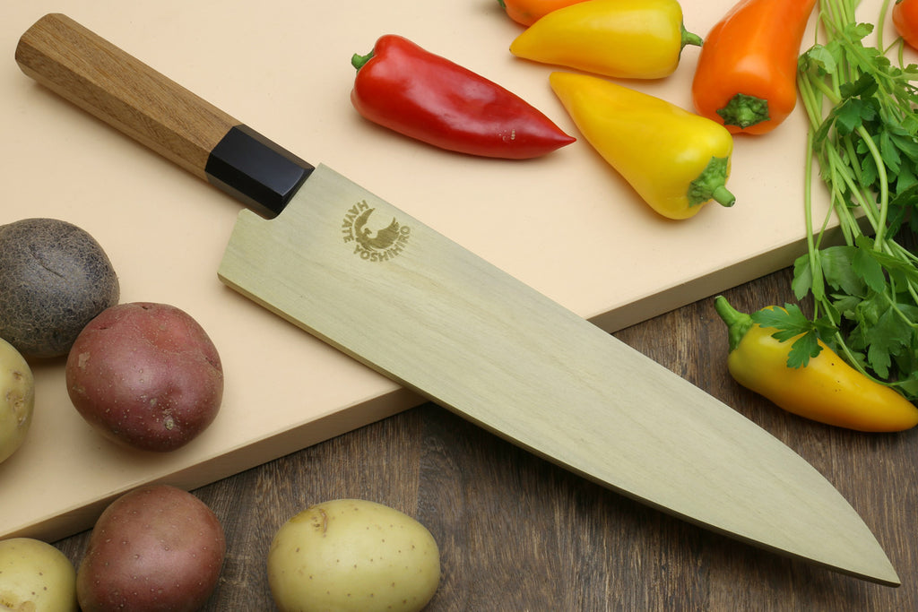 Damascus gyuto chef's knife with light octagonal handle and black bolster on board