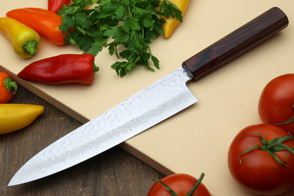 Japanese chef's knife angled view with hammered Damascus blade and dark rosewood handle