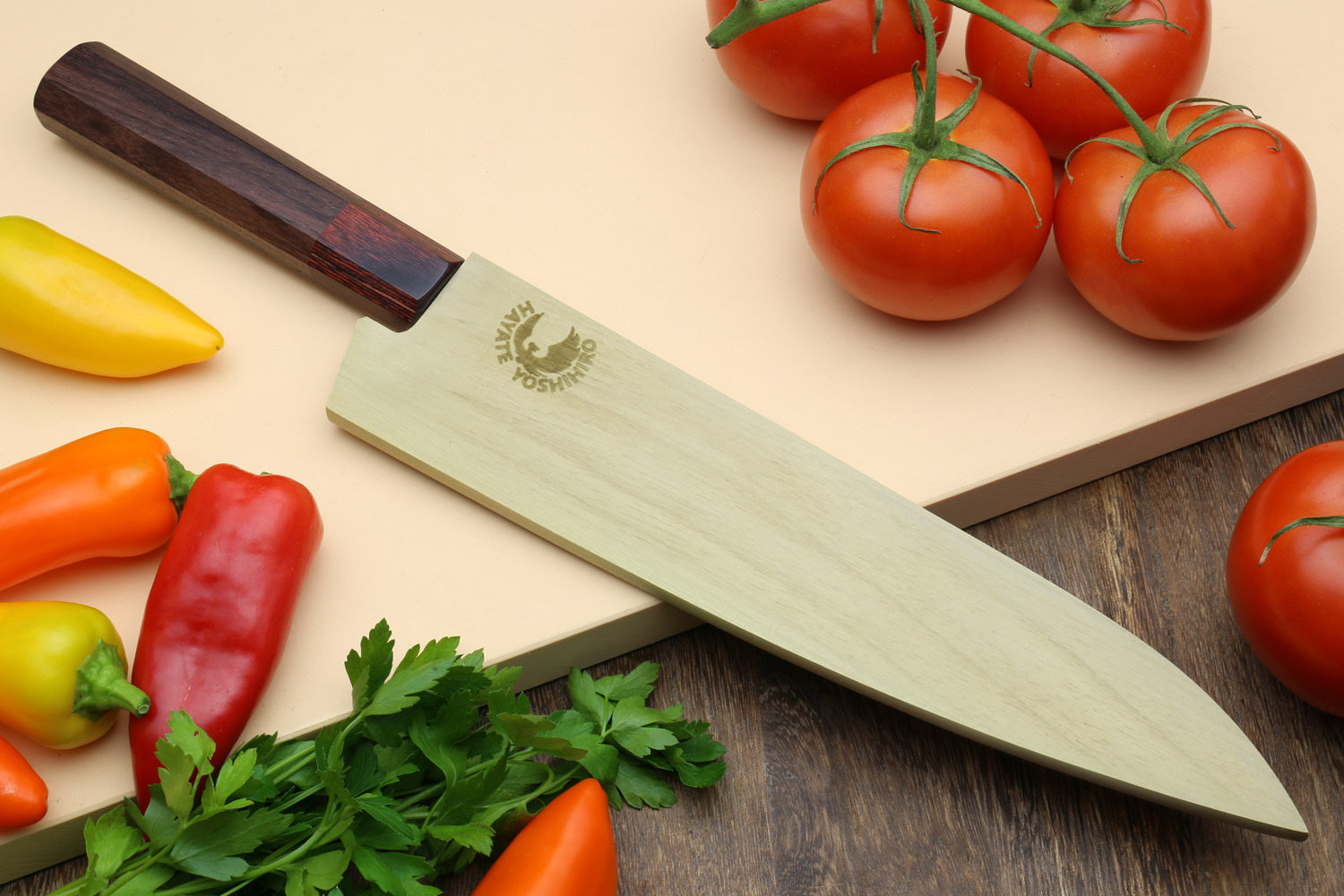 Japanese chef's knife resting on wooden board with hammered Damascus blade and rosewood handle