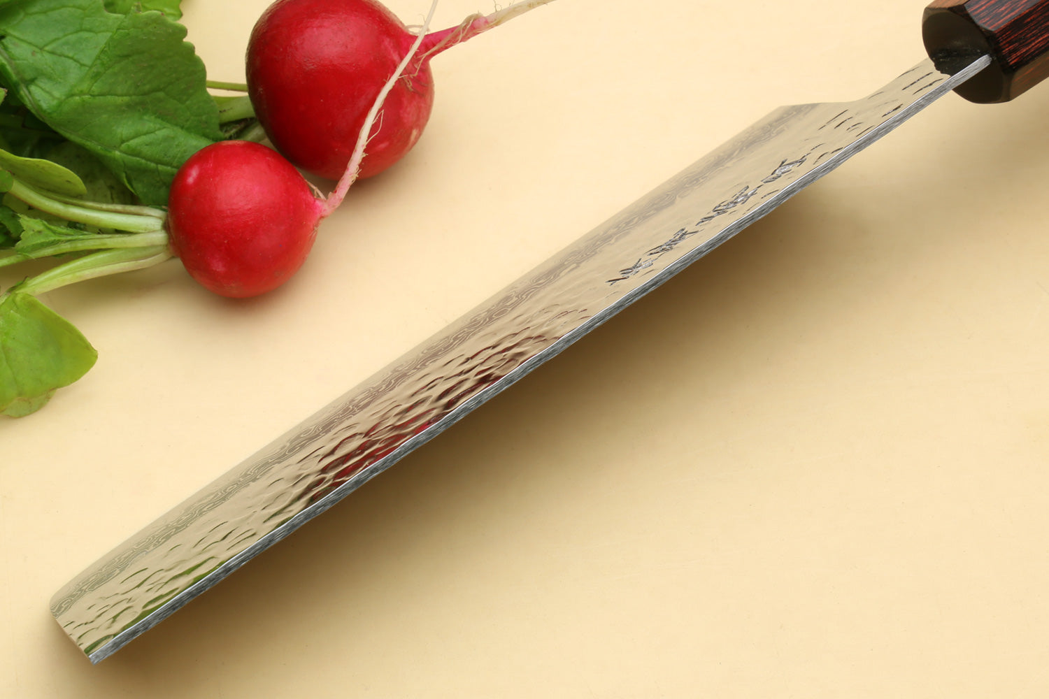 Nakiri vegetable knife showing hammered Damascus blade edge and dark rosewood handle