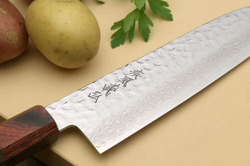 Damascus santoku knife blade close-up with carved kanji marks and dark octagonal handle.