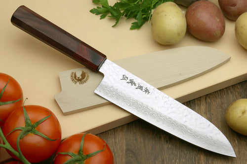 Damascus santoku knife with octagonal dark wood handle and wavy blade, next to tomatoes.
