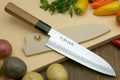 Santoku chef knife with hammered Damascus blade and dark handle on a light cutting board