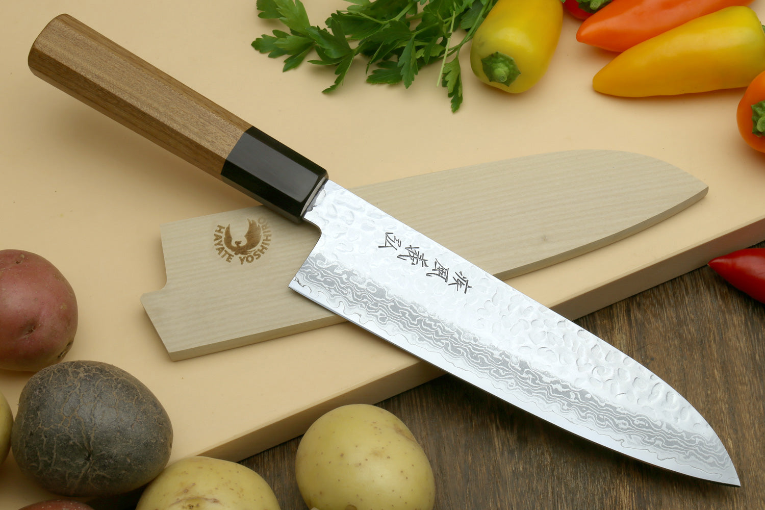 Santoku chef knife with hammered Damascus blade and dark handle on a light cutting board