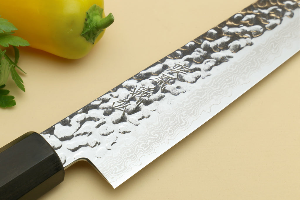 Damascus sujihiki slicer knife blade close-up with hammered pattern and black bolster