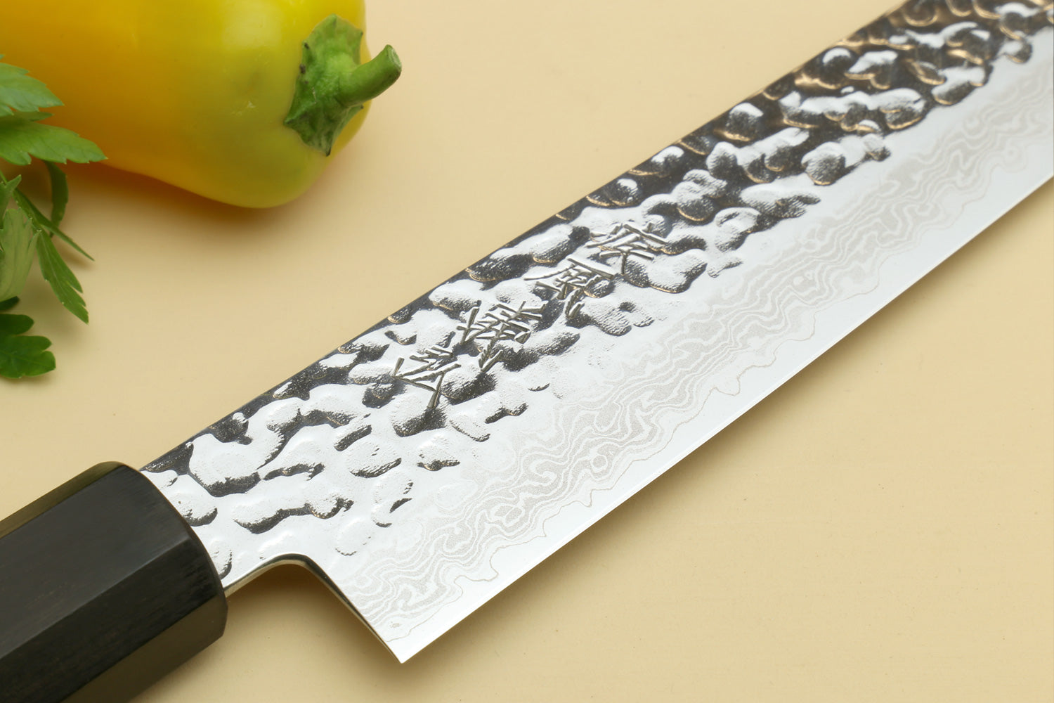 Damascus sujihiki slicer knife blade close-up with hammered pattern and black bolster
