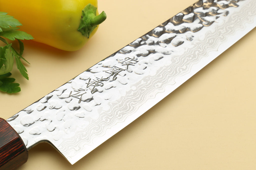 Damascus sujihiki slicer knife blade close-up with engraved markings and hammered pattern