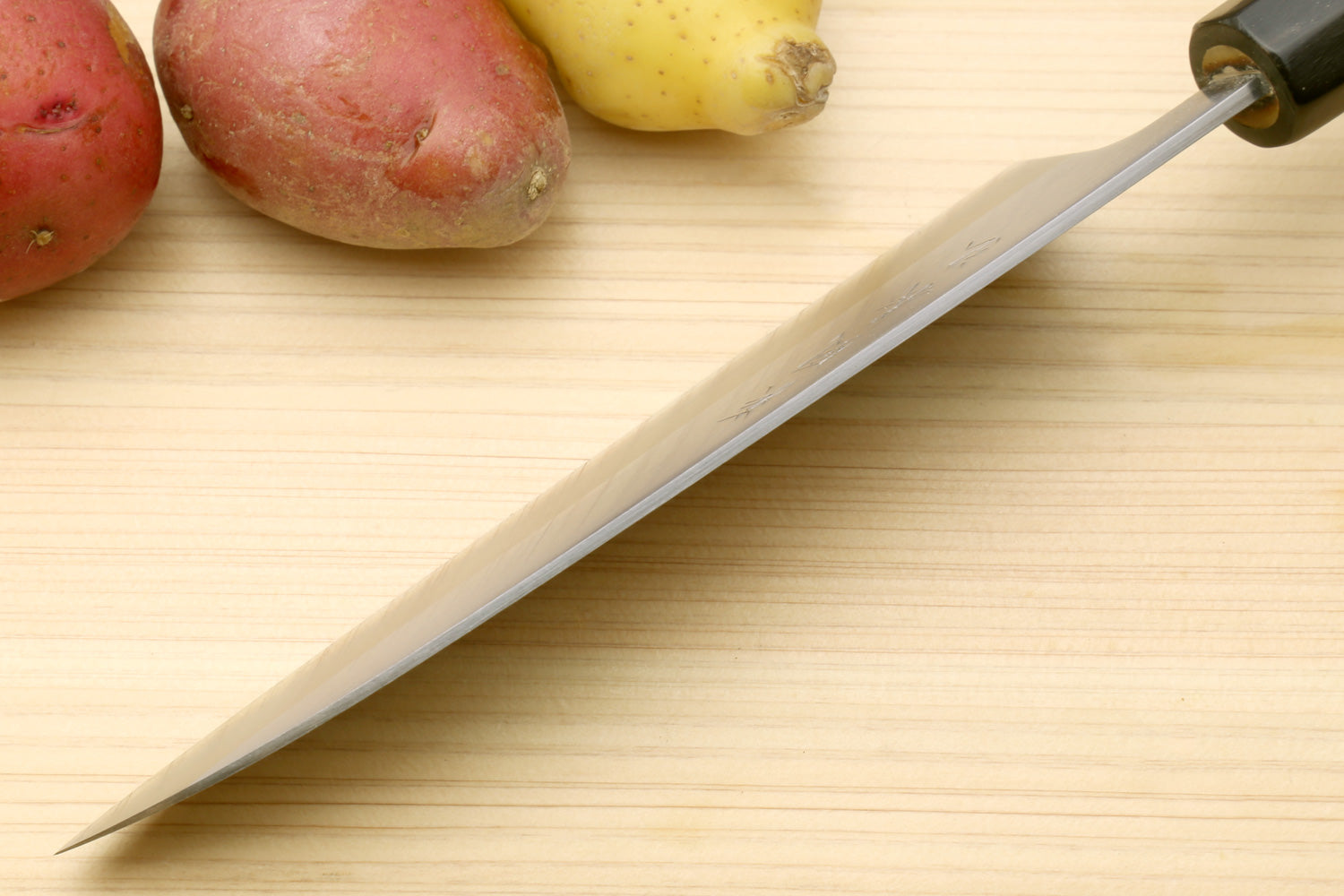 Stainless santoku knife with magnolia wood handle and dark bolster, blade profile