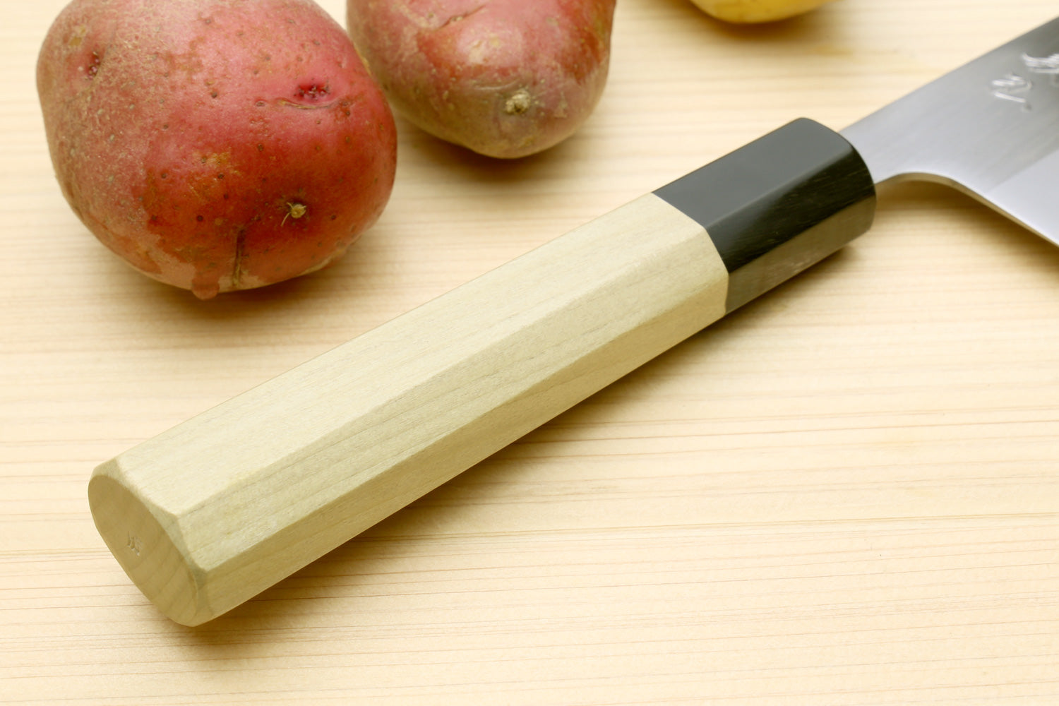 Stainless santoku knife with magnolia wood handle and dark bolster, handle end view