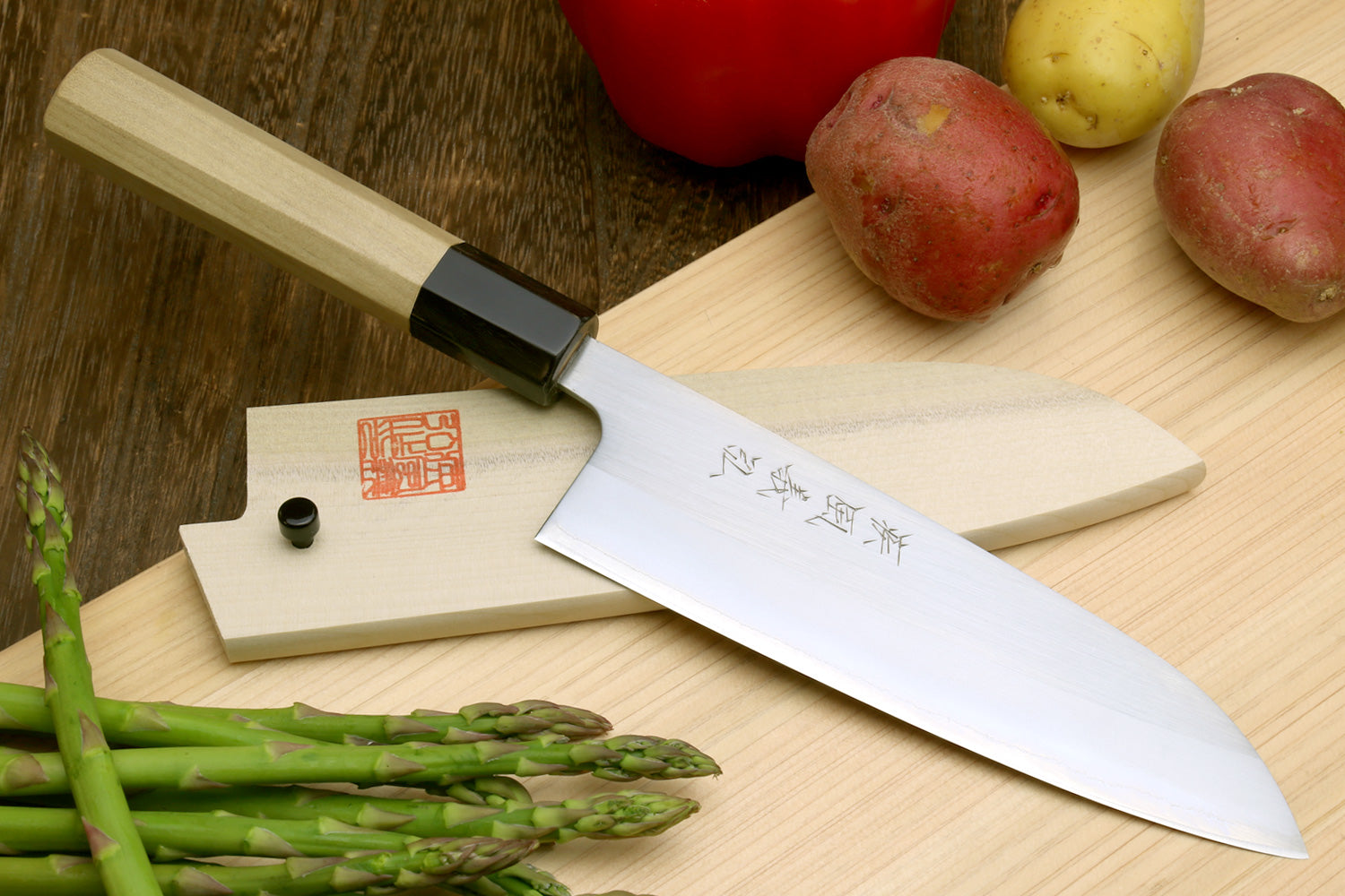 Stainless santoku knife with magnolia wood handle, dark bolster, and engraved kanji