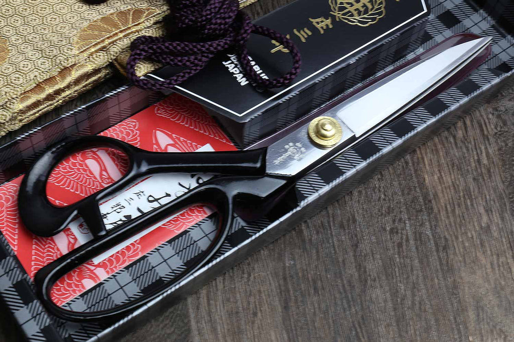 Fabric scissors with black handles, purple bow details, and silver blades