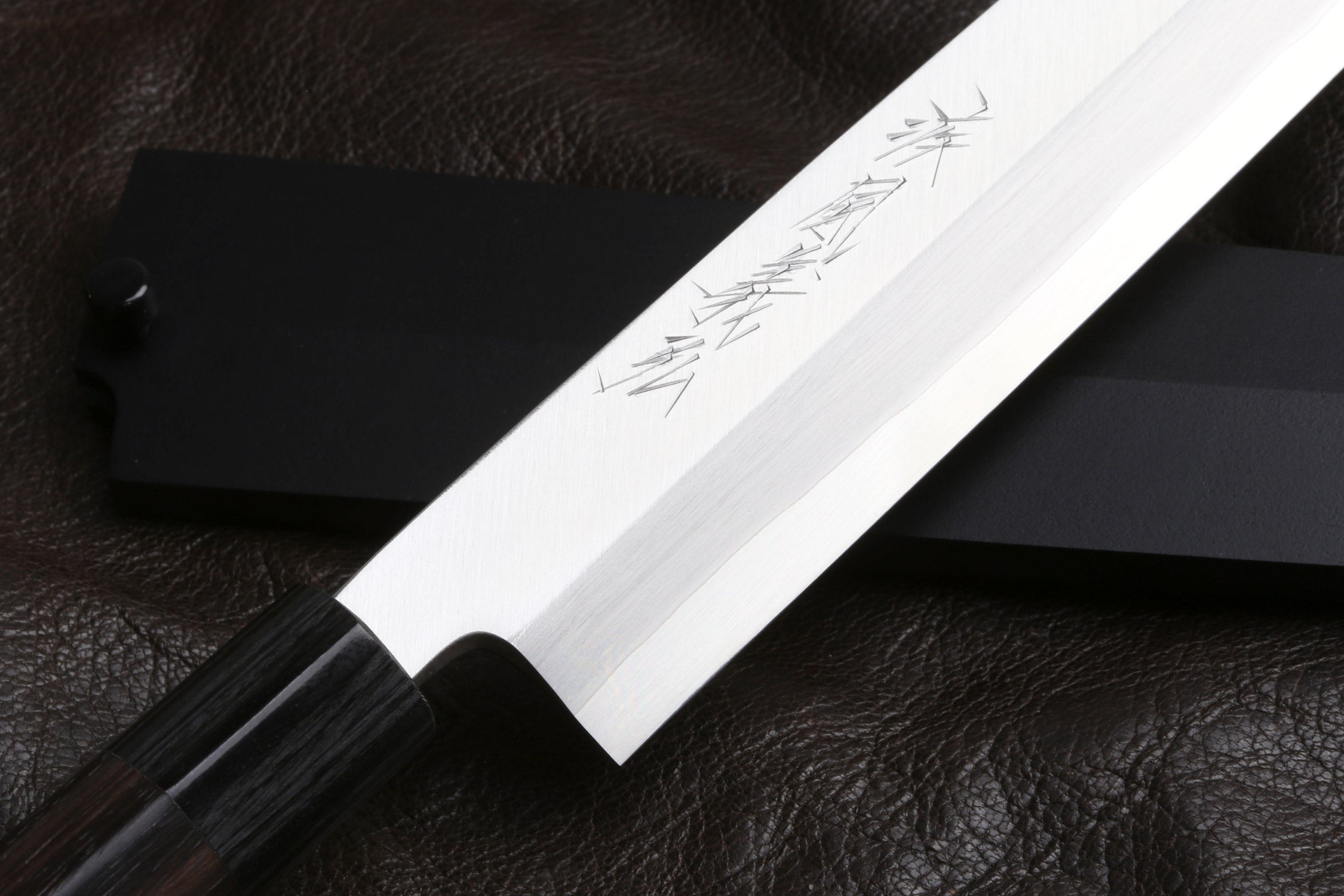 Stainless Yanagi knife blade close-up with etched markings and sharp tip