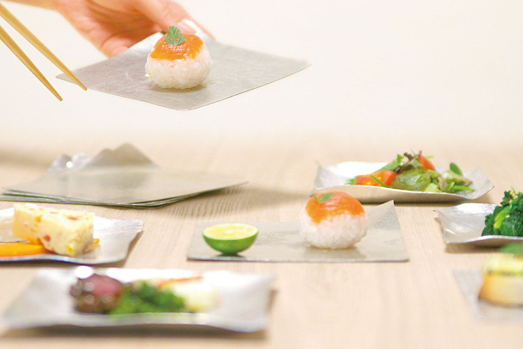 Flexible tin plates on a table with small food portions and chopsticks