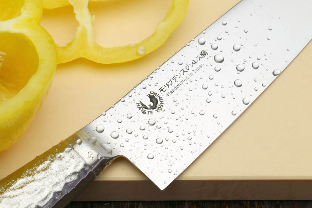 Santoku chef's knife close-up of hammered blade with water droplets