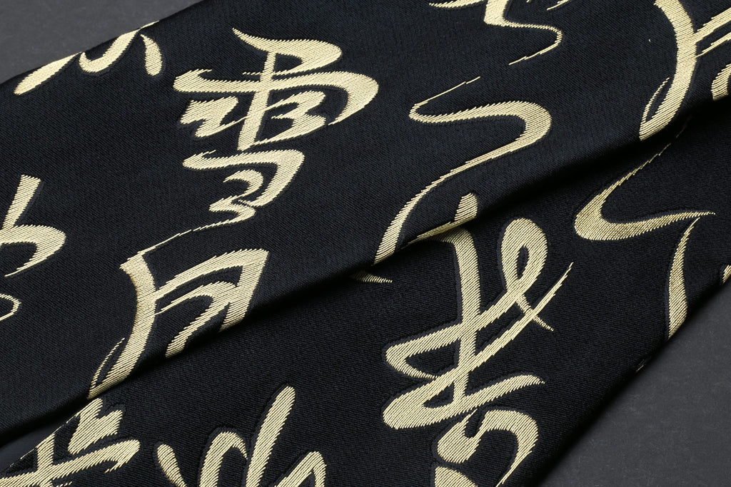 Black Japanese knife pouch bag with gold kanji calligraphy pattern, close-up