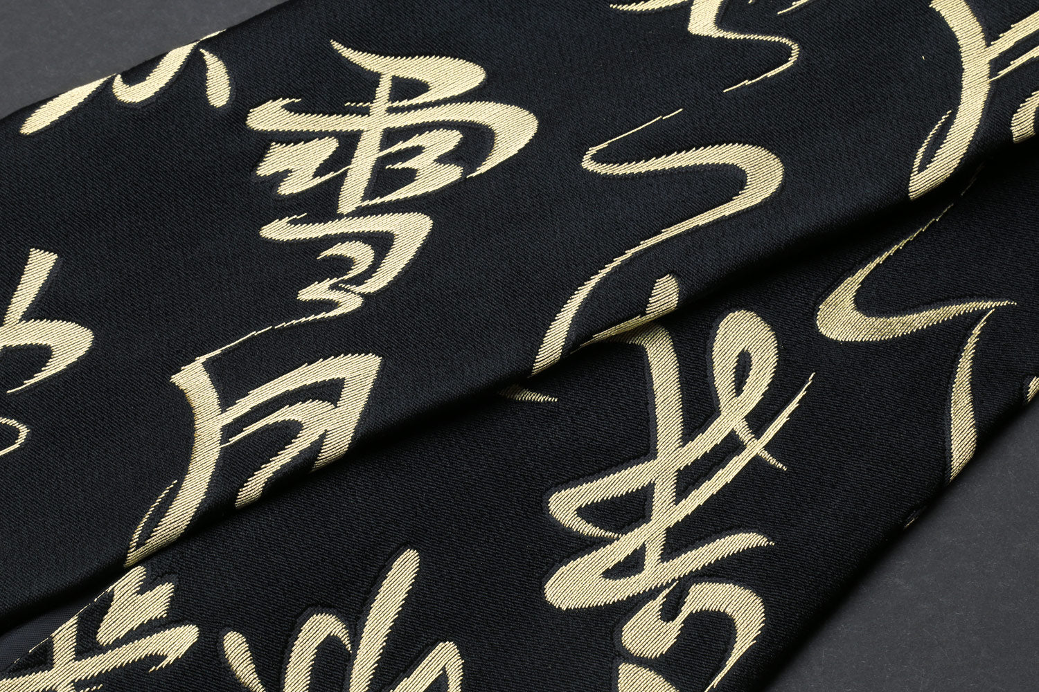 Black Japanese knife pouch bag with gold kanji calligraphy pattern, close-up