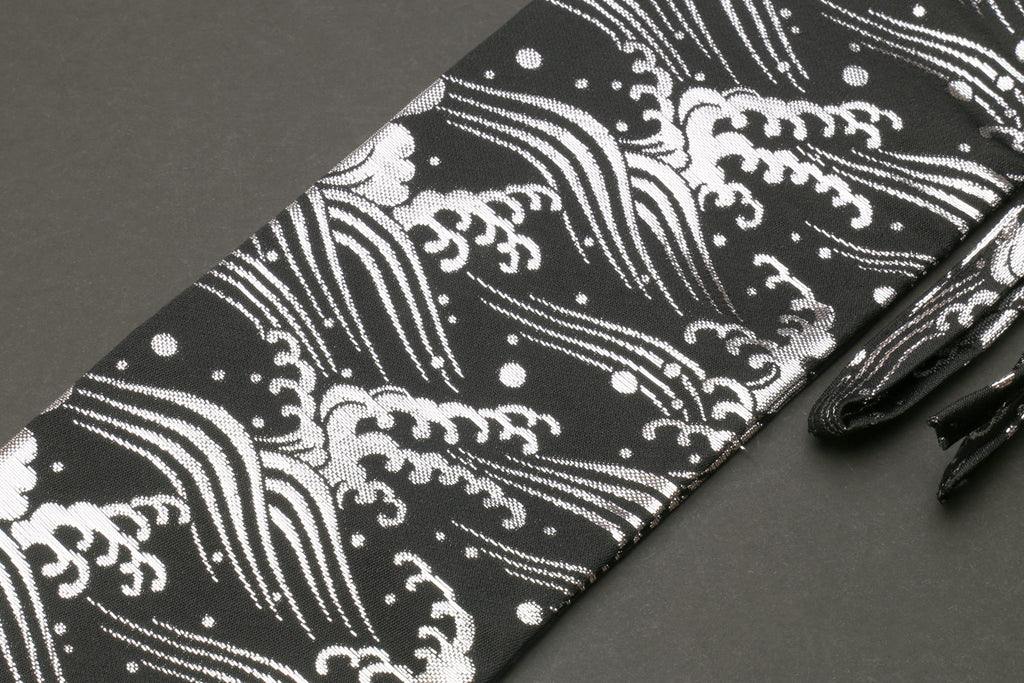 Knife pouch bag close-up: black cloth with white wave motifs and dots, folded edge