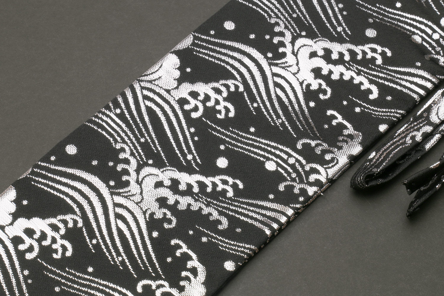 Knife pouch bag close-up: black cloth with white wave motifs and dots, folded edge