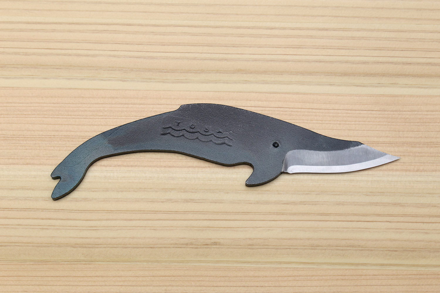 Whale-shaped utility knife with dark steel finish and silver cutting blade