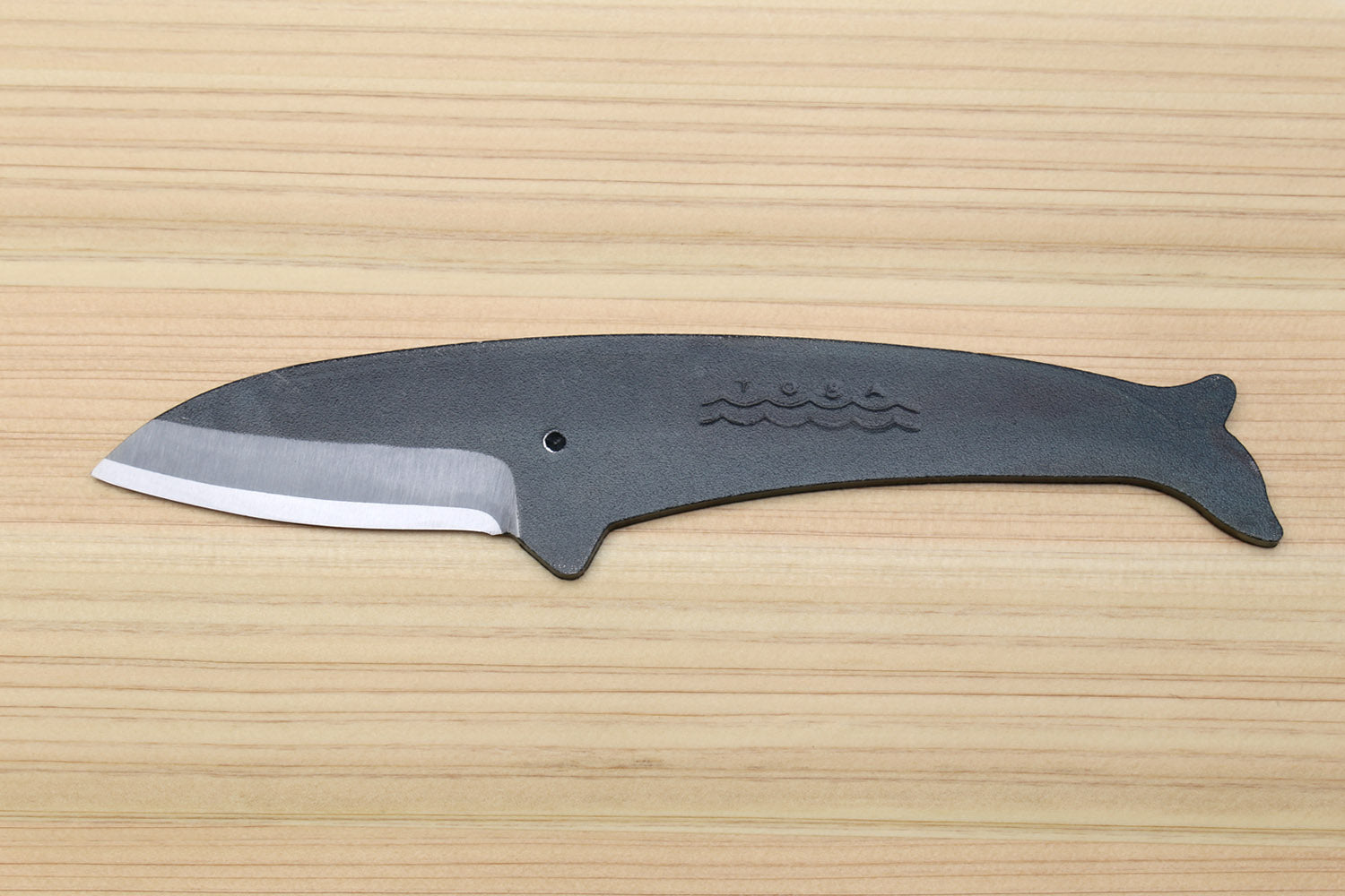 Whale utility knife with dark blue handle, silver blade edge, wavy emblem