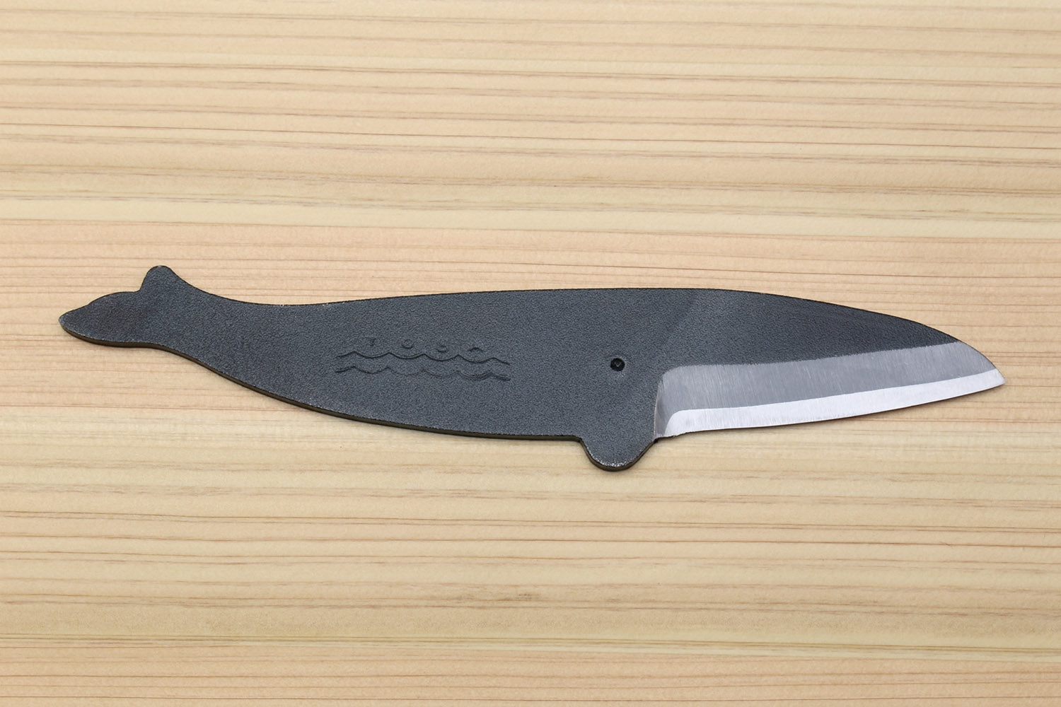 Japanese utility knife with dark handle, wave-engraved bolster, and silver edge