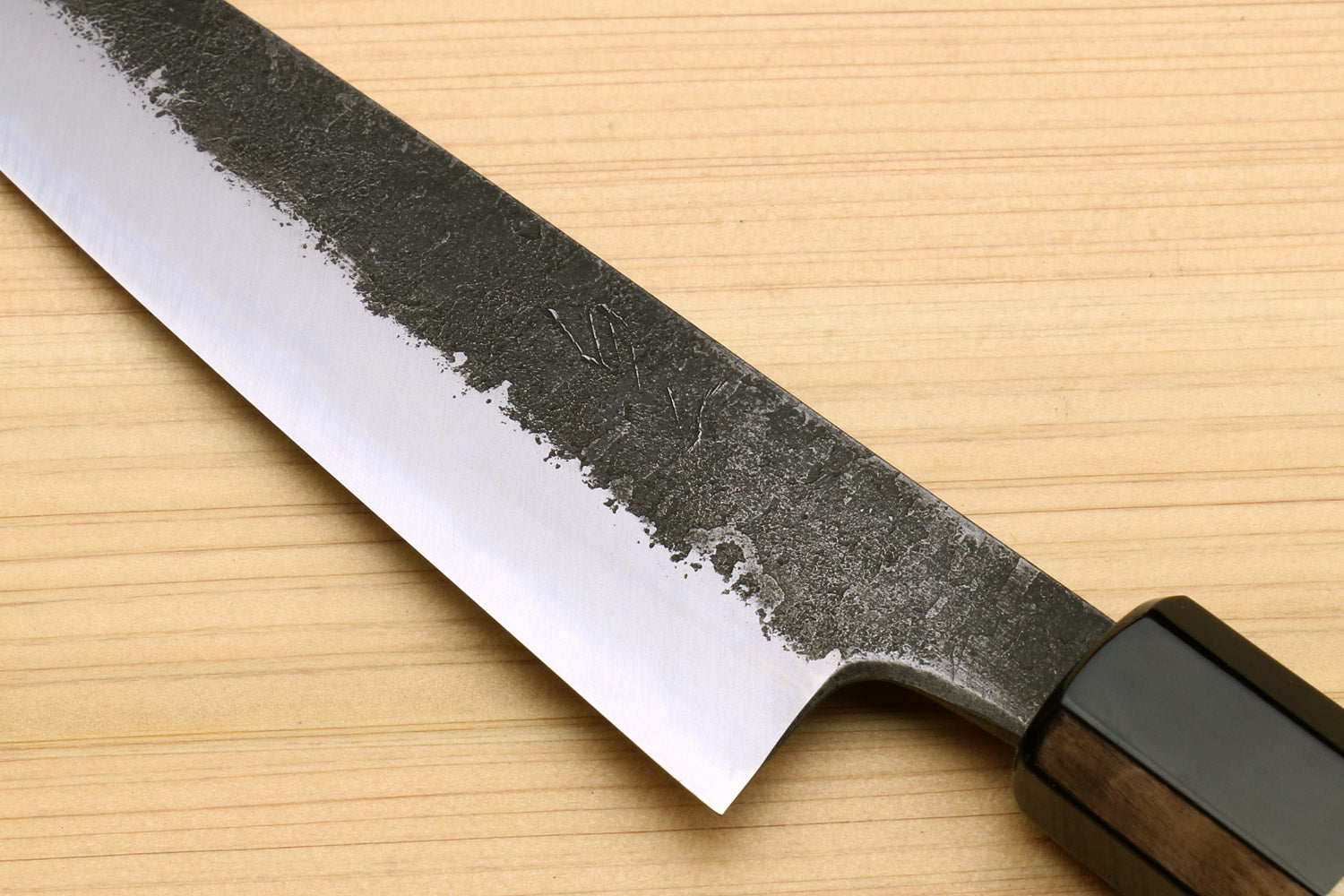 Petty utility knife with speckled steel blade and dark bolster on wood handle