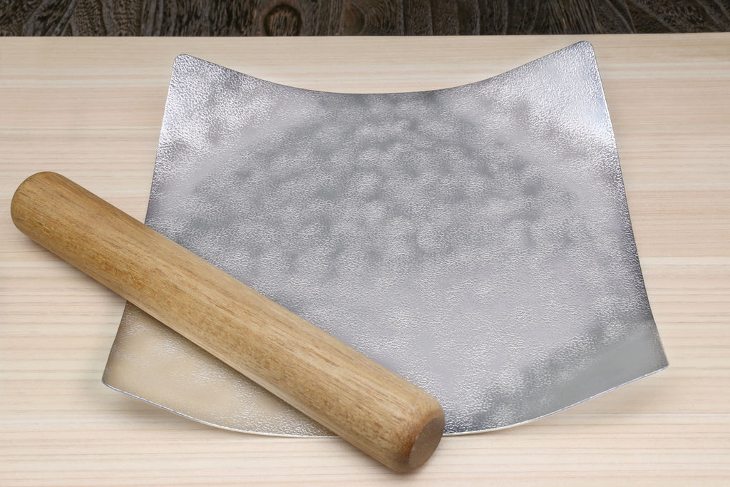 Flexible silver tin plate with a wooden rolling stick placed beside it