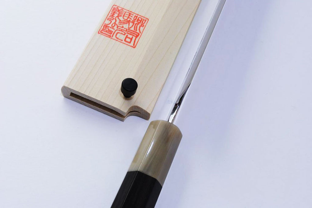 Wood knife saya with red seal and black knob; kiritsuke blade partially inserted