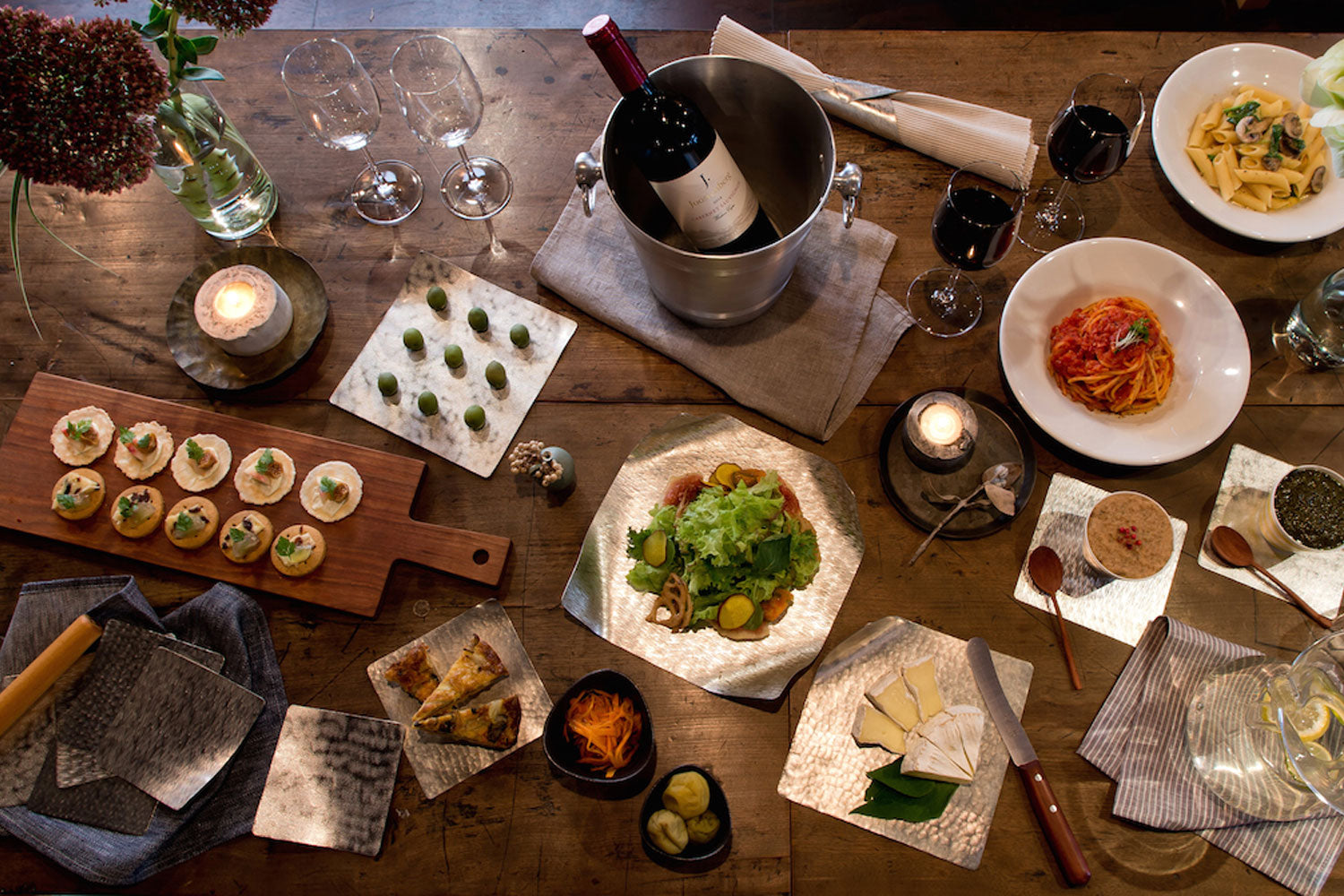 Multiple flexible tin plates with small dishes, drinks, and serving utensils