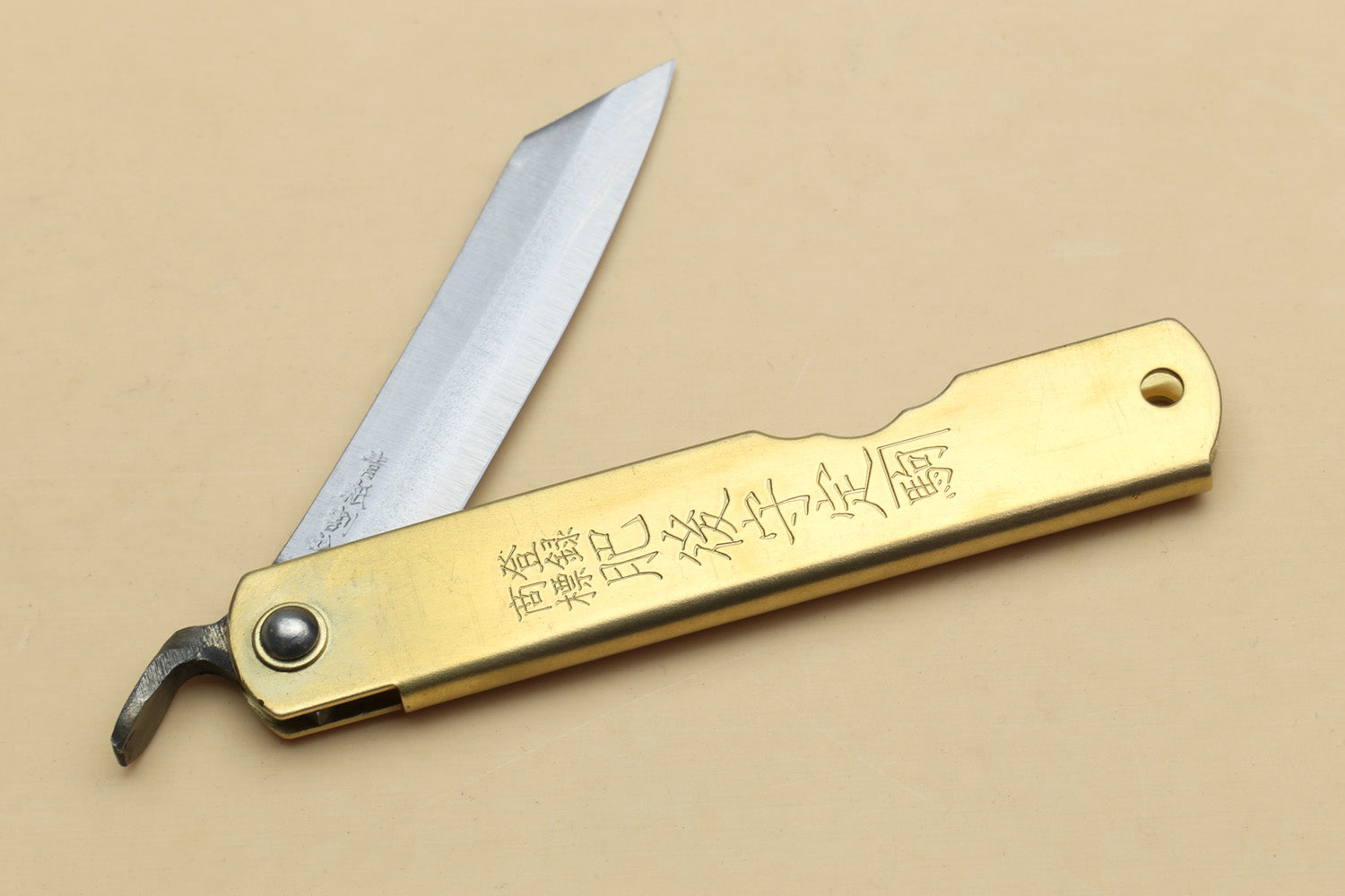 Kiridashi pocket knife with gold handle, thumb notch, and etched pointed blade